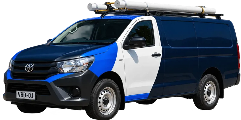 A licensed Cheltenham plumbing van loaded with pipe on the roof rack